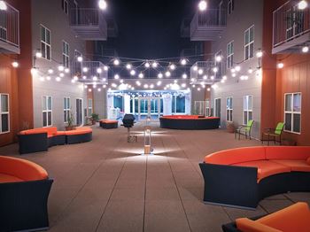 an open area with orange couches and chairs and string lights